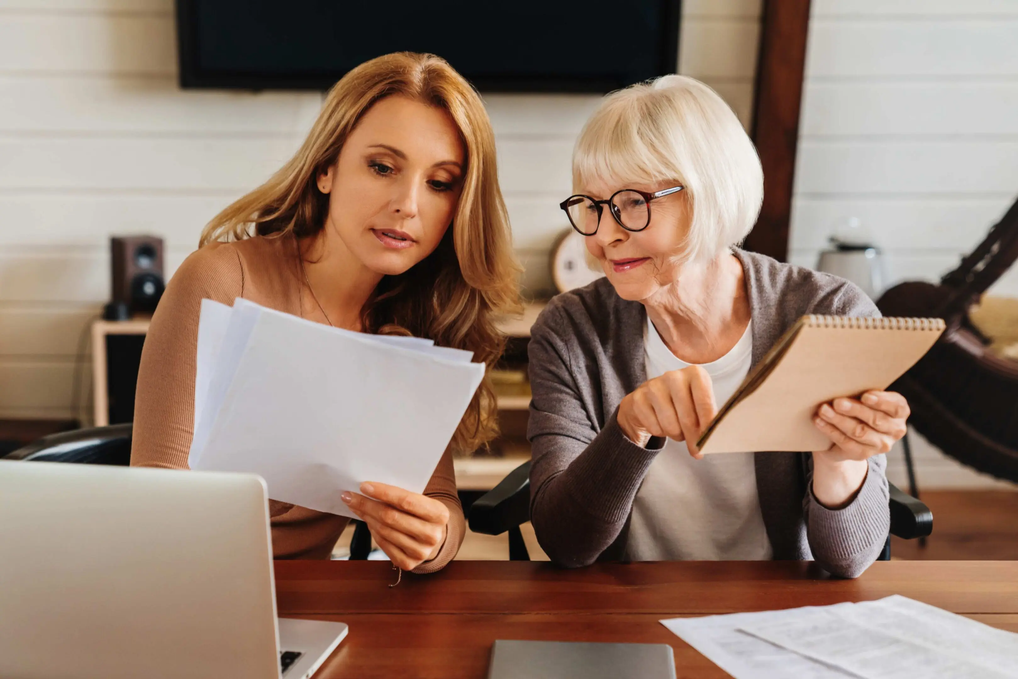 Two women reviewing documents at desk.