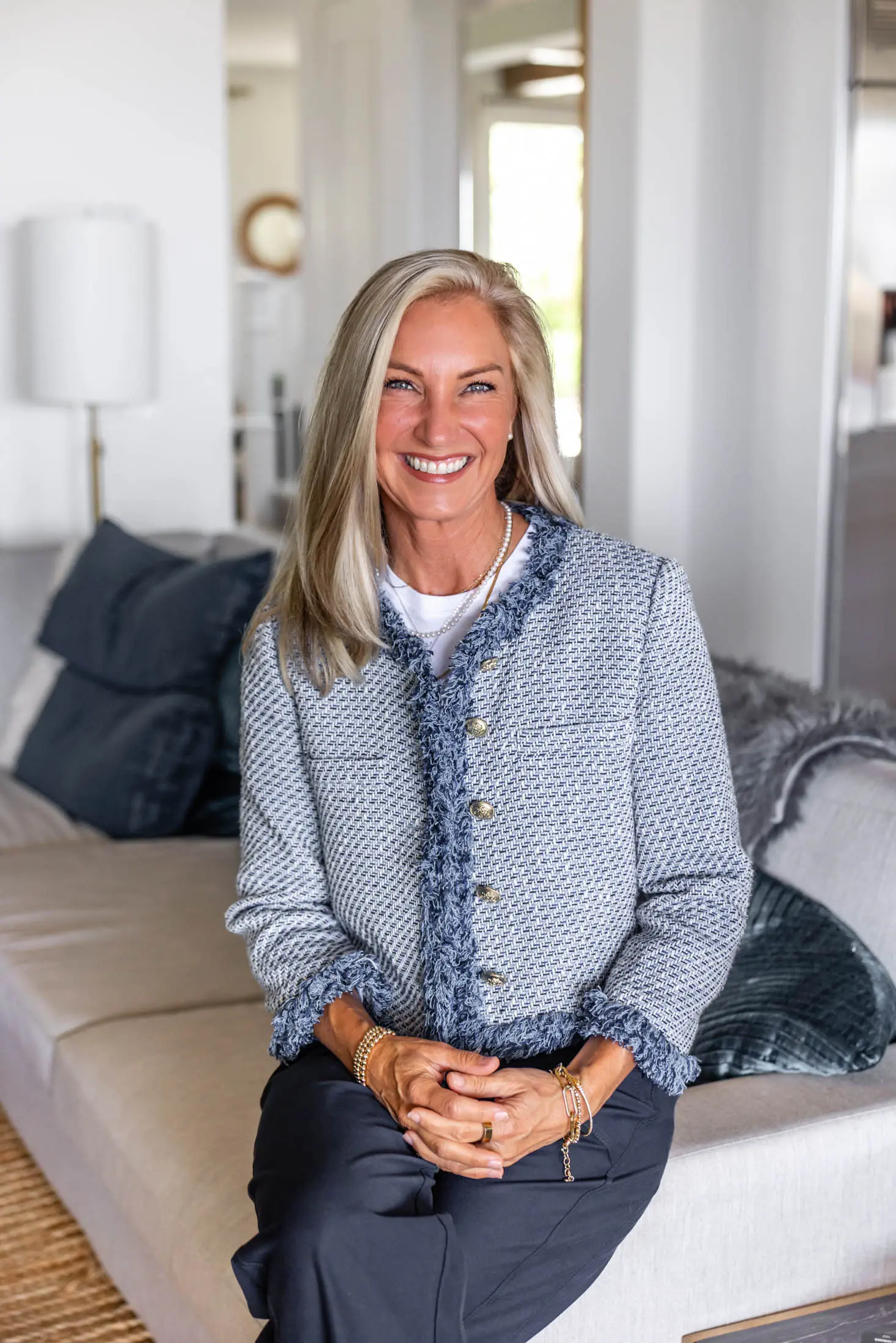 Smiling woman sitting on a beige sofa.
