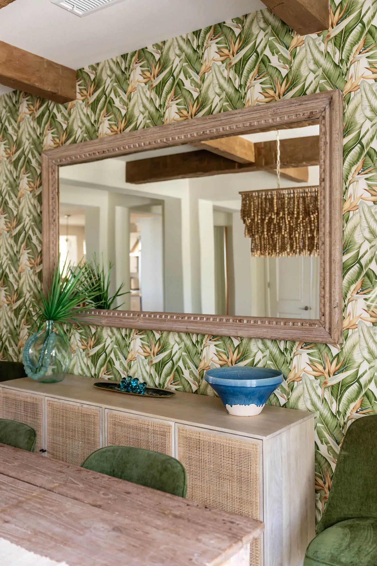 Tropical-themed dining room with large mirror.