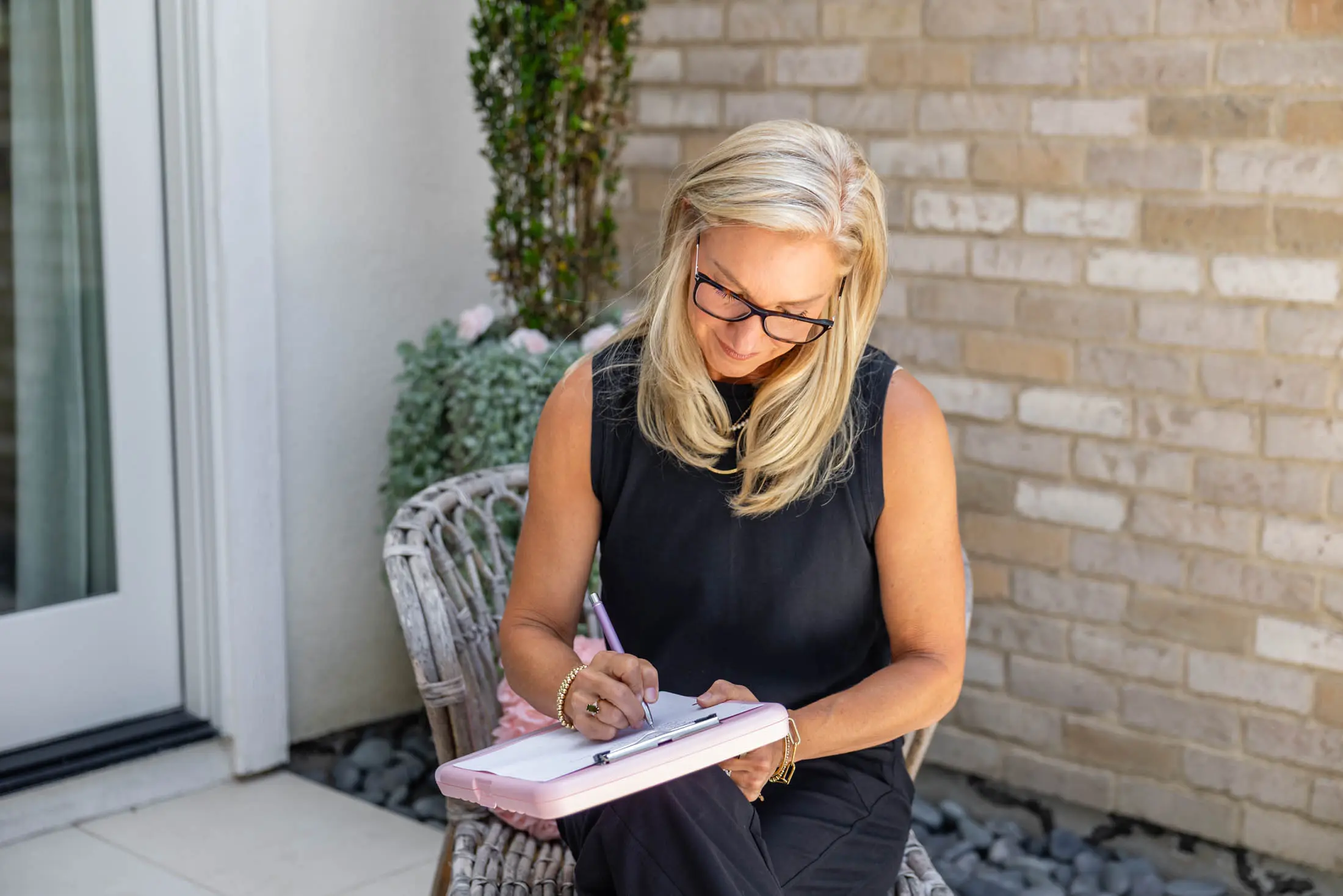 Woman writing on a clipboard outside.
