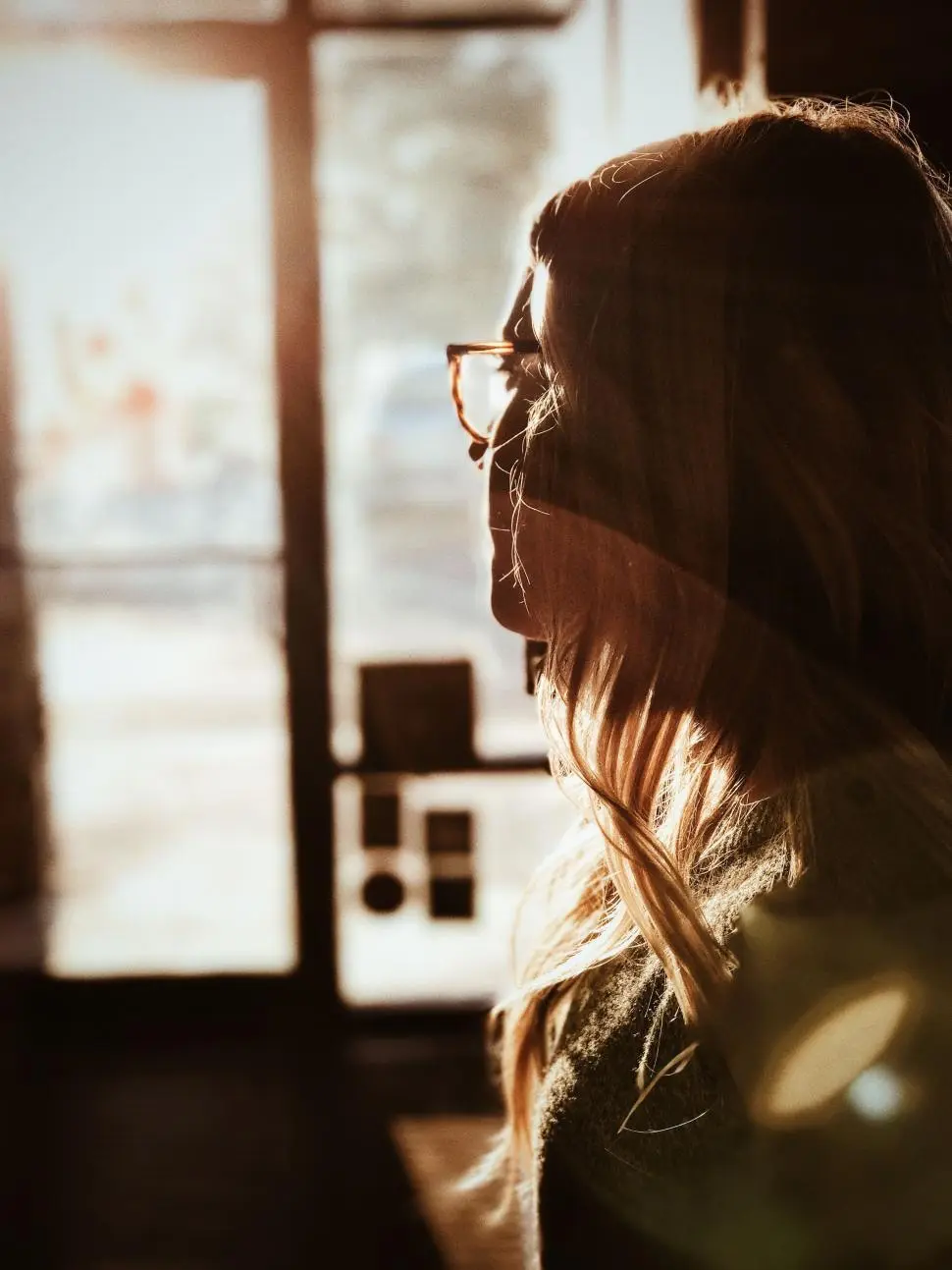 Woman in sunlight near a window.