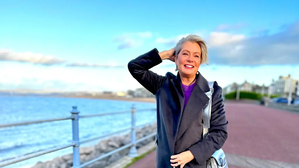 Smiling woman walking along seaside promenade.