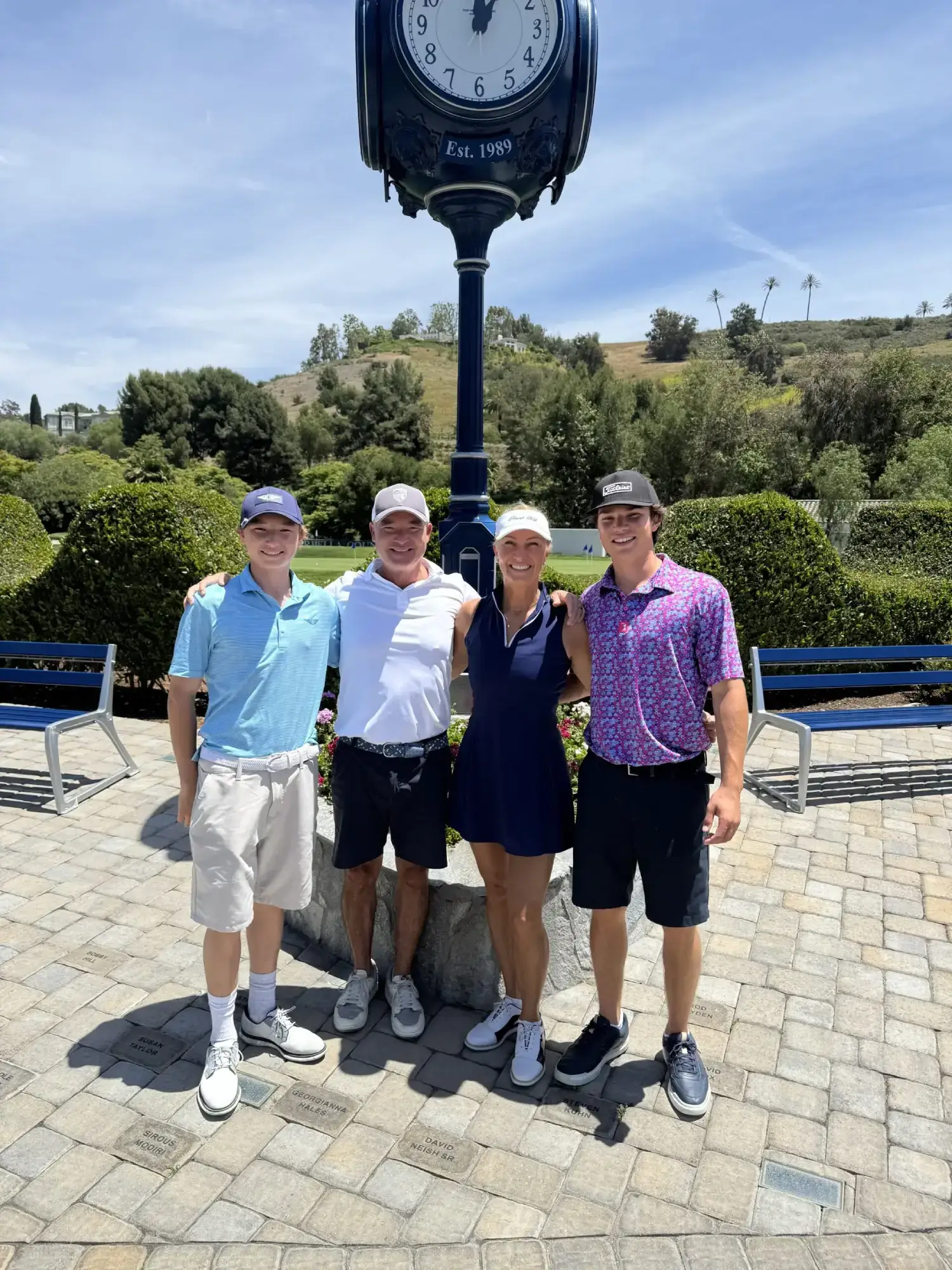 Four people posing under a large clock.